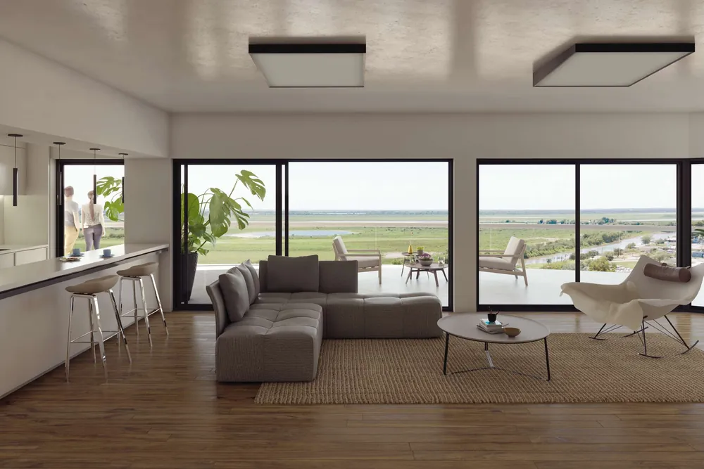 El living de un departamento: sillón, barra de cocina con banquetas y ventanales al balcón y al río